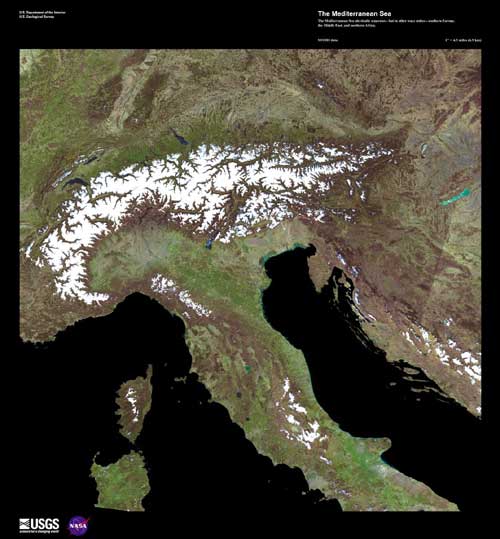 The greens and browns of southern Europe. Snow-capped peaks are at Italy's northern border. The Mediterranean Sea is black.